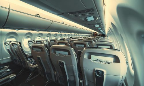 An empty airliner cabin, seats A wide-angle view of the long empty airplane cabin with rows of seats inside of a modern aircraft, with paper safety instructions put to the back seats pockets